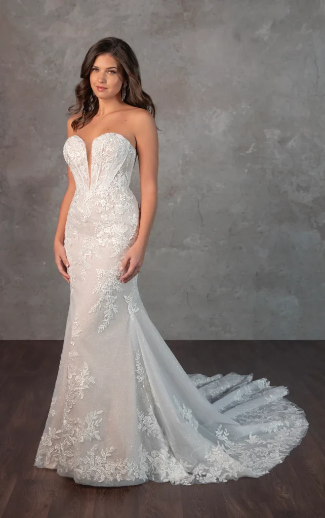 A breath taking lace masterpiece, Capri exudes the beauty and luxury of a designer wedding gown. The strapless plunging sweetheart neckline accentuates the intricately structured bodice, where architectural corsetry blends old world romance with contemporary fashion. Exposed beaded boning and detailed lace appliques create a mesmerizing effect, cascading over the fit-and-flare skirt before flowing into a shimmering, dream-like train adorned with lace accents. The result is a striking and sophisticated bridal look designed to captivate from every angle. This gown is also available in plus sizes in the bodice-lined option.